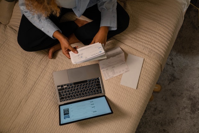 Overhead shot of a person sitting on a bed working on a laptop